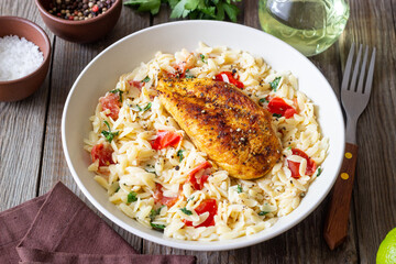 Orzo pasta with fried chicken breast, tomatoes and herbs. Italian food.