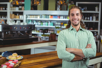 Espresso machine steaming beside colorful pastries on wooden counter under warm pendant lighting