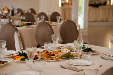 Elegant Wedding Reception Table Setting with Gourmet Appetizers, Glassware, White Linens, and Soft Lighting in a Bright Banquet Hall