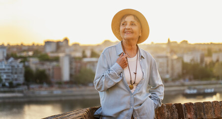 Beautiful senior woman enjoying sunset overlooking european city