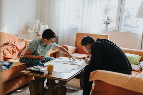 Two family members enjoying quality time together while playing a strategic game in a comfortable and well-lit living room space, representing leisure and bonding moments. - Powered by Adobe
