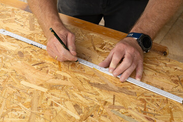 Ein Heimwerker beim Anzeichen mit Zollstock und Bleistift, Hobby Holzbau 