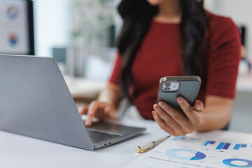 Businesswoman working with laptop and smartphone at office desk
