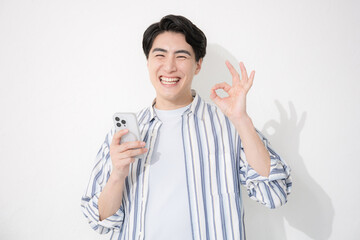 シャツを着た男性　カメラ目線スマホで笑顔のokやgoodのポーズ	
