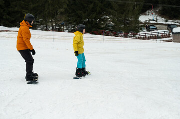 Exciting snowboard adventure on a winter day in a snowy landscape with vibrant jackets and focused expressions of joy and learning