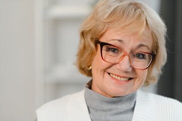 Fototapeta premium Portrait of happy senior woman standing at home. Cheerful retired old lady relaxing at home