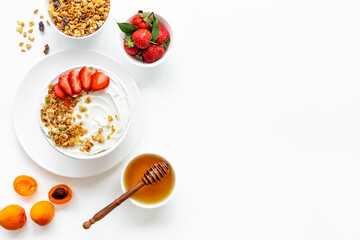 Bowl with yogurt and oatmeal served with honey and strawberry, top view