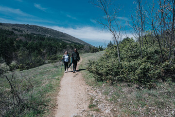 Fototapeta premium A couple enjoying a scenic hike on a nature trail in a mountainous area under clear blue skies.