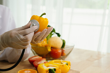 A gloved hand, resembling a doctor's, holds a tomato while using a stethoscope, symbolizing food...