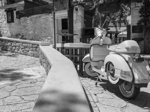 Fototapeta Black and white photo of an old town with red retro scooters in italy