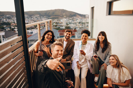 Friends enjoying an evening gathering on a rooftop with drinks and laughter