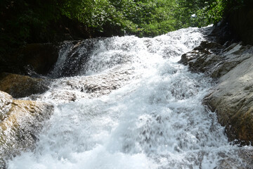 Naklejka premium Raging waterfall flowing over rocky cliffs in a lush green setting