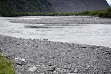 Smooth river rocks lining a tranquil riverbed in natural landscape