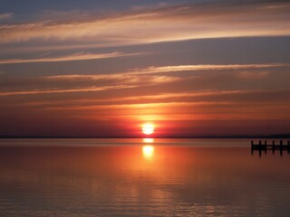 Obraz premium Serene sunset over calm water with distant dock