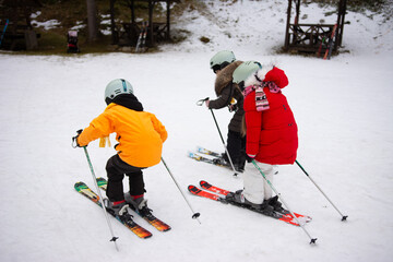 A group of excited children eagerly learning the joys of skiing on a beautifully snowy hill, enjoying a winter afternoon adventure at a vibrant ski resort