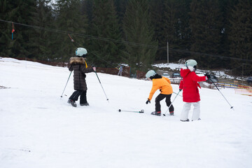 Skiing lessons for kids on a snowy slope surrounded by tall trees in a winter wonderland, capturing...