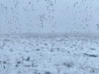 water drops on glass surface, view through car window with rain drops, winter landscape through the...