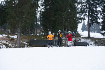 Three young skiers prepare for an afternoon of adventure on a snowy slope in a serene mountain area...