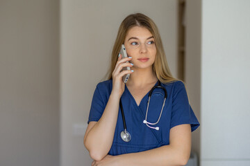 Female nurse talking on phone wearing blue scrubs with stethoscope