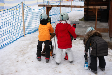 Children prepare for a fun day of skiing in the winter wonderland with fluffy snow and exciting...