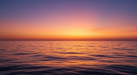 Fototapeta premium Serene sunset over calm ocean waters, displaying vibrant hues of orange and purple in the sky.