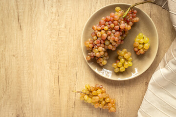Plate full of ripe yellow grapes, top view