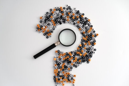 A black loupe positioned at the center of scattered letters and numbers forming a large question mark, symbolizing curiosity, analysis, and the search for answers
