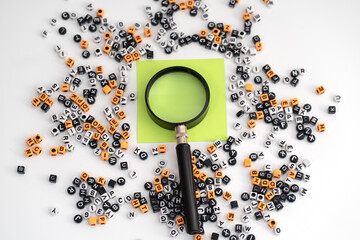 A blank of green paper magnified under a magnifying glass, surrounded by a scattered assortment of...
