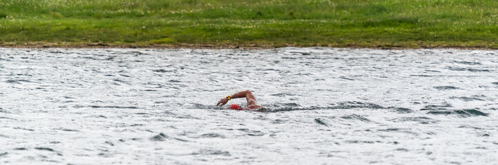 Ein Sportler schwimmt in einem See bei leichtem Wellengang
