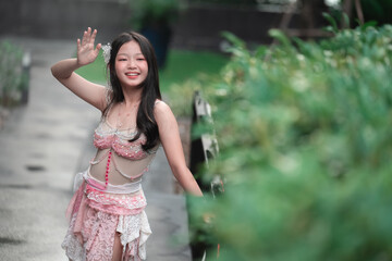 Fototapeta premium Young girl in traditional attire smiling and waving outdoors