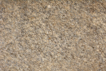 A close-up of a beige or light brown granite texture with darker specks