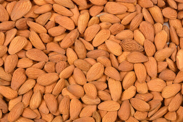 A close-up, top-down shot of a pile of raw almonds, showcasing their natural texture and color.