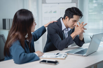 Businesswoman providing comfort to her stressed businessman colleague while collaborating on a...