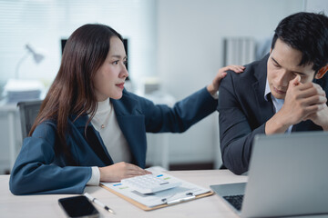 Asian business people experiencing stress in the office, with a businesswoman comforting her upset...