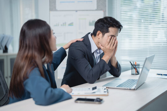 Businesswoman providing comfort to her stressed male colleague in the office, demonstrating empathy and support during challenging times in the corporate environment