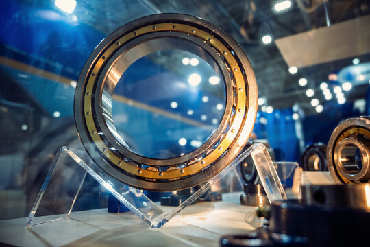 Large industrial bearing on display, showcasing metal technology and engineering precision in a factory setting. Blurred background with lights.
