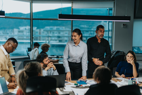 Multiracial business team collaborating in a contemporary office setting, focusing on innovative ideas and teamwork. The atmosphere is dynamic and inclusive, with individuals engaged in discussions.