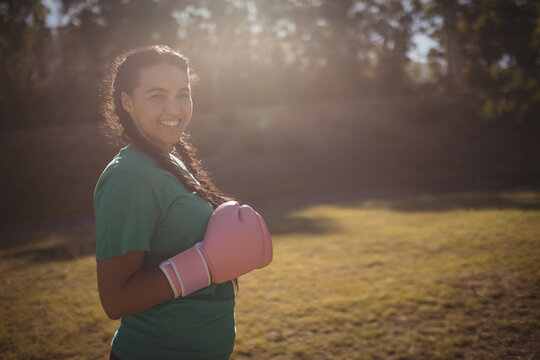 Fototapeta Pink boxing gloves resting in sunlit grass near tree line with warm light filtering