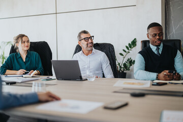 A diverse group of business people engaged in a meeting, showcasing teamwork and collaboration. The...