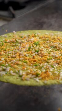 Authentic South Indian pesarattu being prepared on a tawa