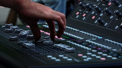 Close up of sound technician moving faders of the soundboard during summer music festival