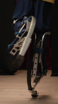 Vertical cropped shot of legs of unrecognizable person bouncing on jumping stilts performing tricks of powerbocking on stage