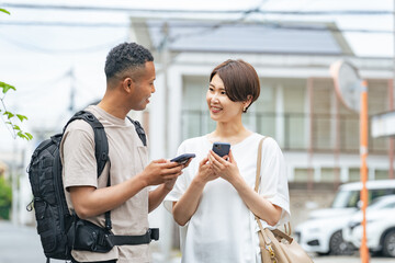 スマホの翻訳アプリを使って黒人男性と会話する日本人女性