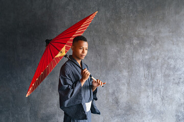 A black man wearing a Japanese yukata and holding a Japanese umbrella