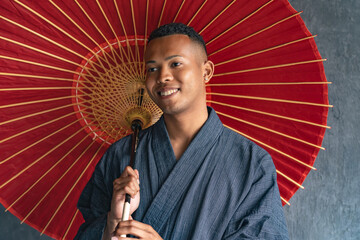 A black man wearing a Japanese yukata and holding a Japanese umbrella