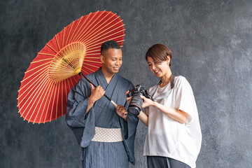 A black man wearing a yukata being photographed by a photographer