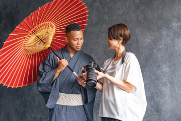 A black man wearing a yukata being photographed by a photographer