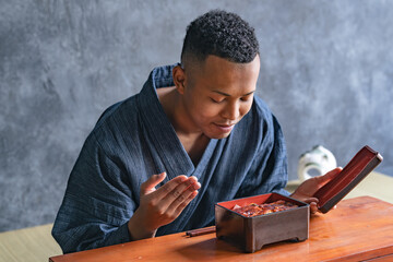 A black man eating eel rice box at a Japanese restaurant