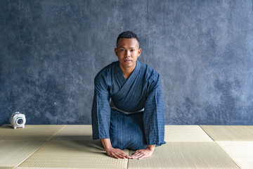 A black man wearing a yukata sitting on a tatami mat