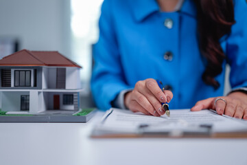 Real estate agent pointing with a pen at a contract document while explaining the details of buying...